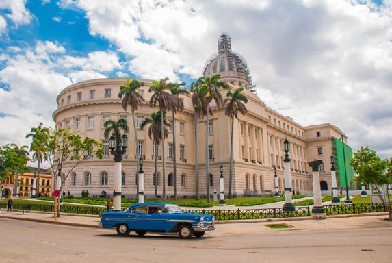 Old car next to the Capitol of Havana