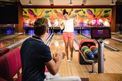 Couple playing bowling in hotel bowling alley