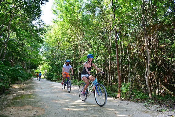 Turistas montando bicicleta en la Riviera Maya