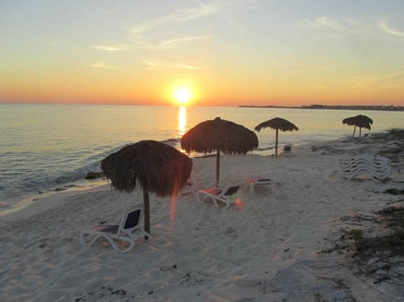 sunset on the beach with sun beds and umbrellas