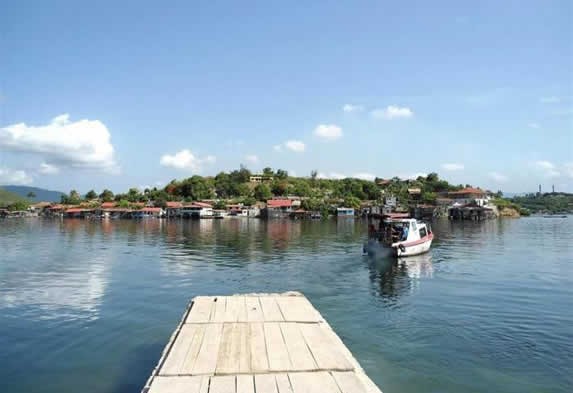 muelle con cayo al fondo y pequeño bote zarpando