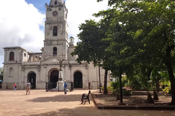 iglesia colonial en la plaza rodeada de árboles