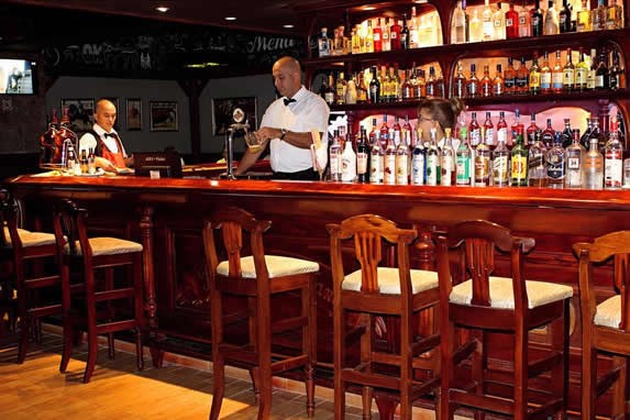 bar with wooden furniture and bottles on shelfs