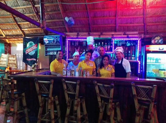 wooden bar with stools under guano roof