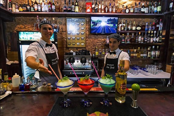 Waiters showing cocktails behind the bar.