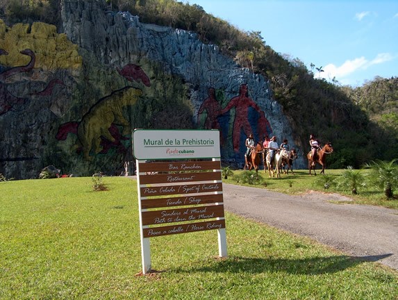turistas montando caballo alrededor del mural