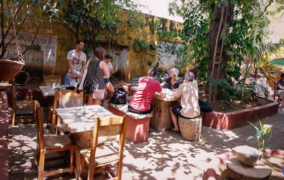 customers at wooden tables surrounded by greenery