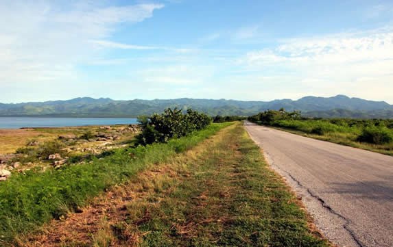 road surrounded by greenery and the sea aside