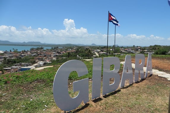 Cartel de Gibara junto a bandera en una elevación