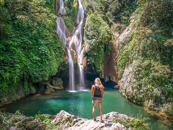 person back to a waterfall with vegetation