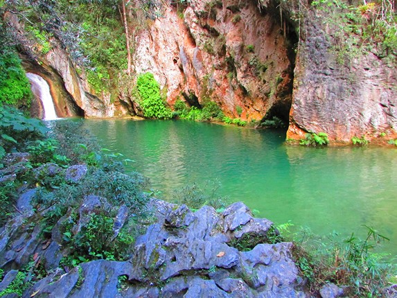 cascada rodeada de grandes rocas y vegetación