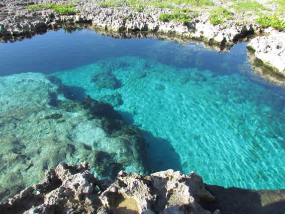 blue water cenote surrounded by rocks