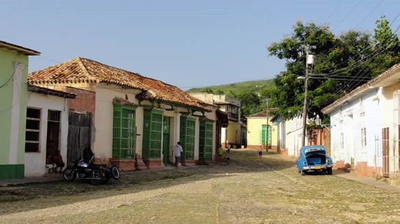 plaza colonial con adoquines y coche clásico azul