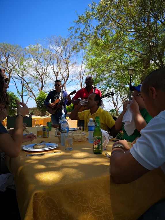 clientes disfrutando su comida y músicos tocando