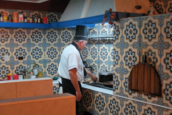 Chef in outdoor kitchen decorated with mosaic.