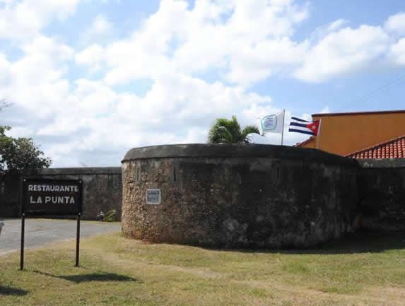 entrada con muro de piedra y cartel