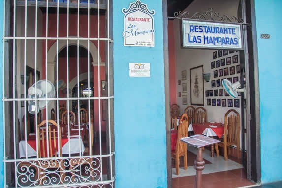 entrada del restaurante con cartel y rejas blancas