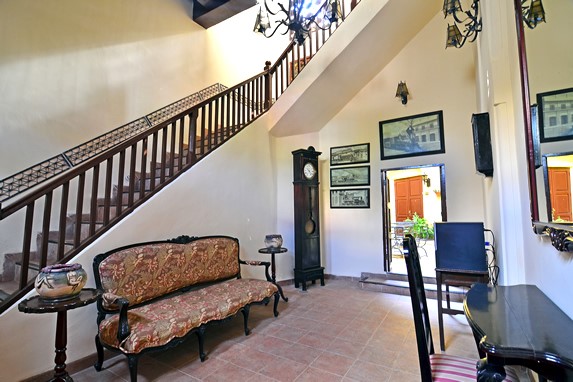 salón con mobiliario antiguo y escaleras de madera
