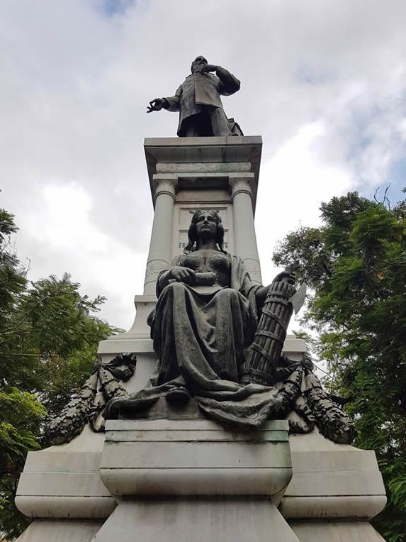 bronze sculpture on marble under blue sky