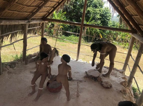 esculturas de taínos bajo techo de guano y madera