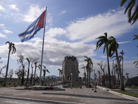 Mausoleum surrounded by palm trees and Cuban flag.