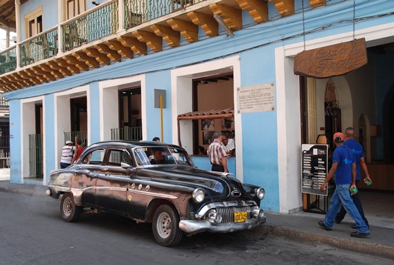 fachada colonial azul con balcones y auto antiguo 