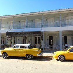 colonial facade and vintage cars parked outside