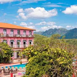 fachada del hotel rodeado de montañas y vegetación