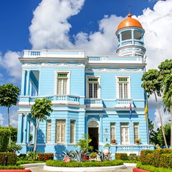 fachada azul del hotel con jardín en frente