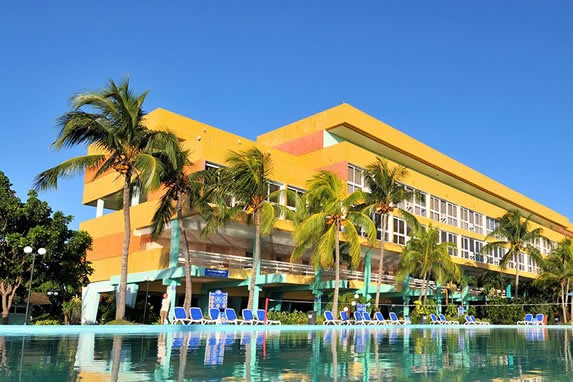 Pool surrounded by sun loungers and palm trees