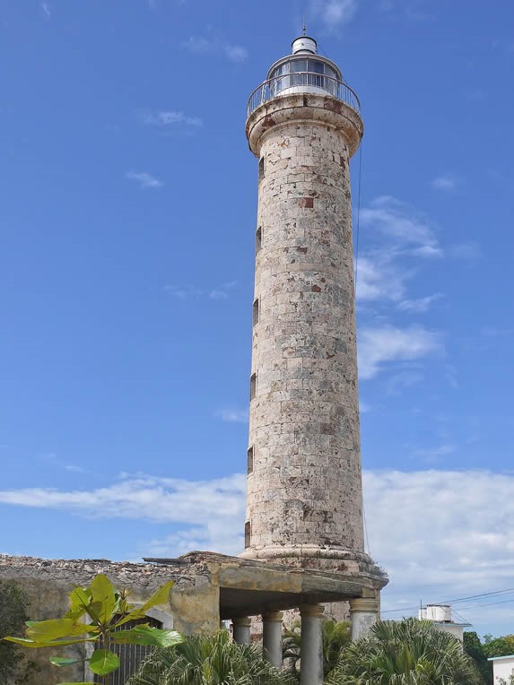 faro rodeado de vegetación bajo el cielo azul