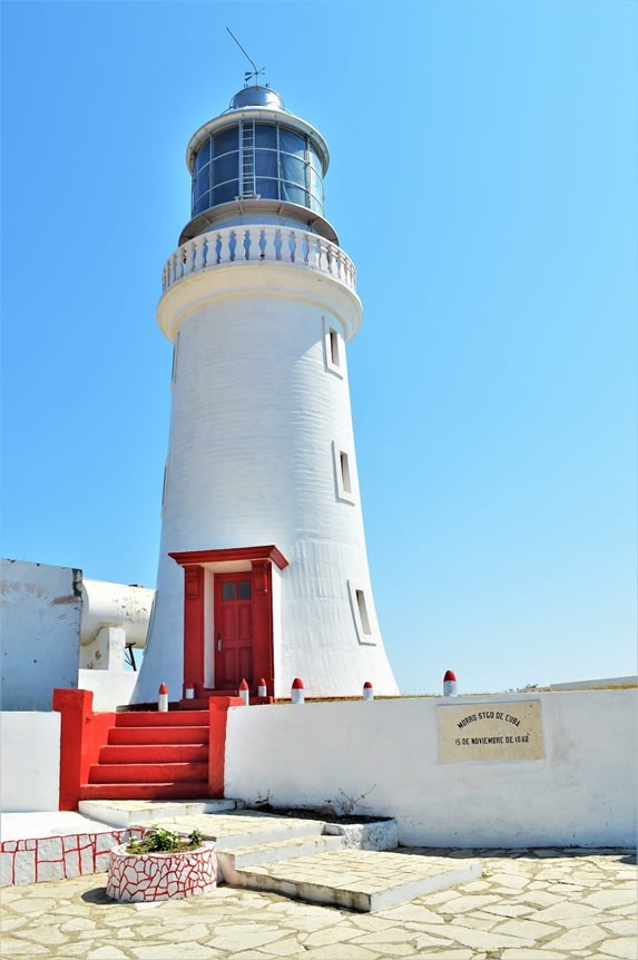 White lighthouse with red doors and stairs.