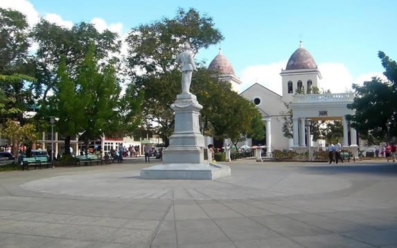 estatua en medio de la plaza rodeada de árboles