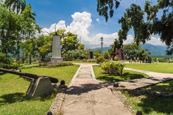 Road surrounded by sculptures and vegetation.