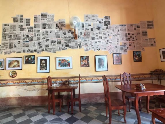 mesas de madera y pared decorada con periódicos 