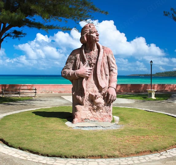 stone statue with the sea in the background