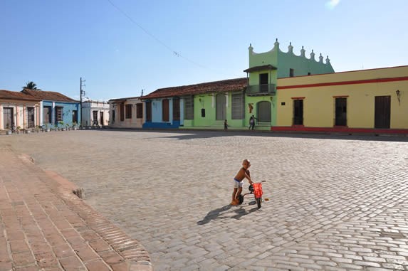 niño jugando en la plaza rodeada de edificaciones 