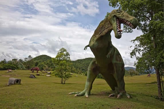 escultura de tiranosaurio rex bajo un árbol