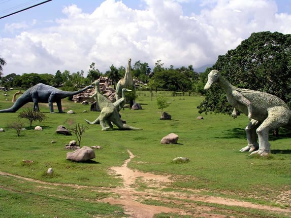 Numerous dinosaur sculptures in a valley.