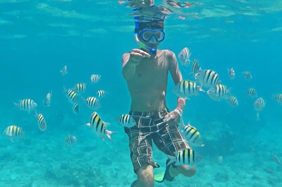 turista con snorkel y alimentando peces