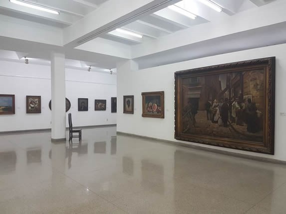 White room with paintings on display.