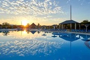 piscina rodeada de palmeras al atardecer