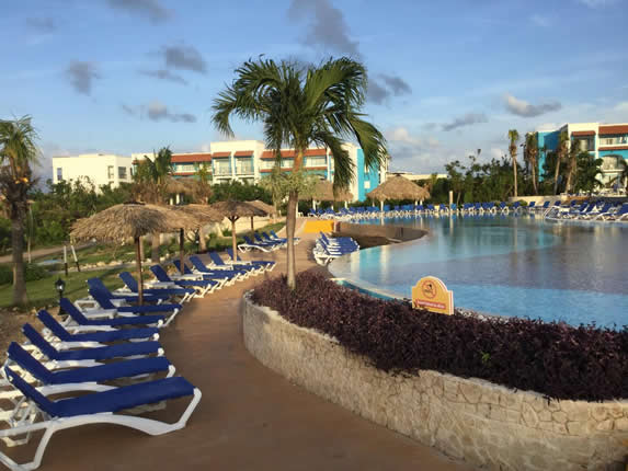 piscina rodeada de tumbonas y palmeras