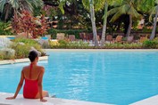 turista en piscina rodeada de plantas y palmeras