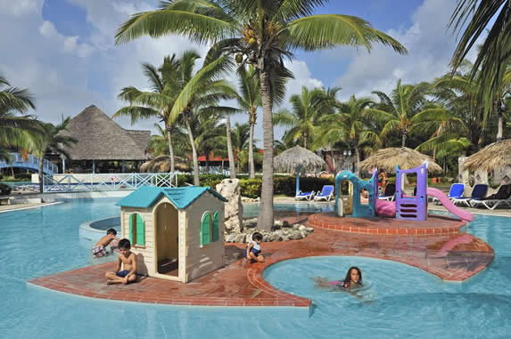 piscina rodeada de palmeras  y sombrillas de guano