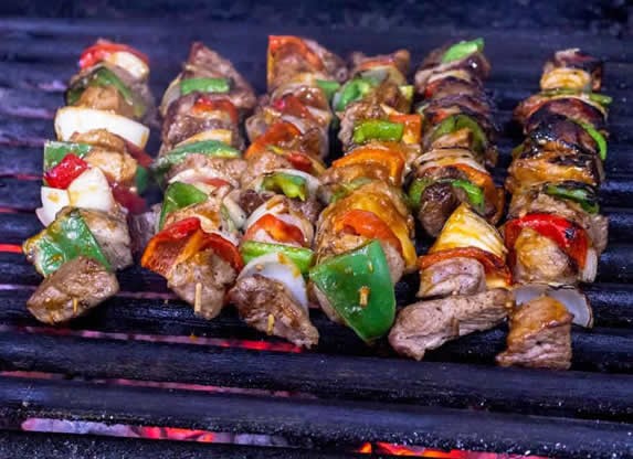 skewers of meat and vegetables on the grill