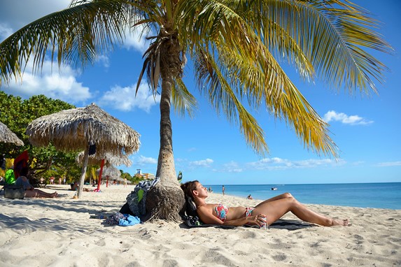 turista descansando sobre cocotera en playa