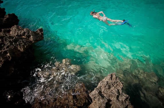 turista esnorqueleando en playa de agua cristalina