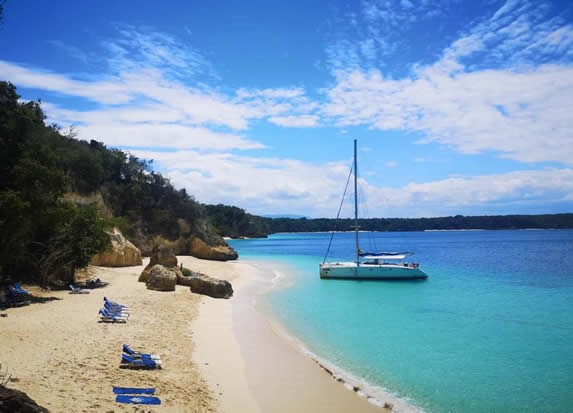 beach with sunbeds and catamaran in the sea