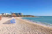playa con sombrillas de guano y tumbonas azules